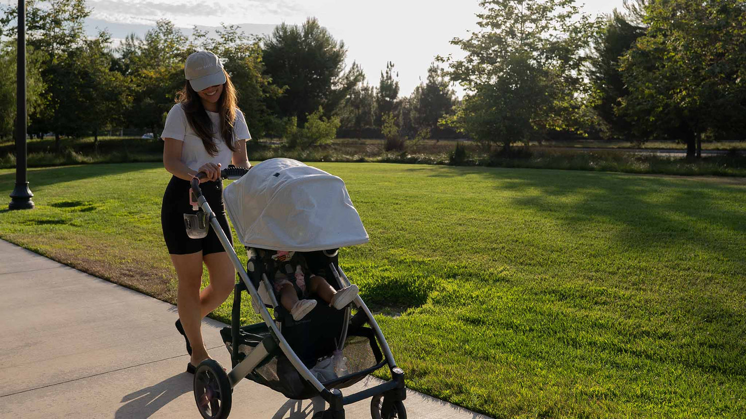 Young Asian American woman walking a baby in a stroller on a bright afternoon in a nice neighborhood trail