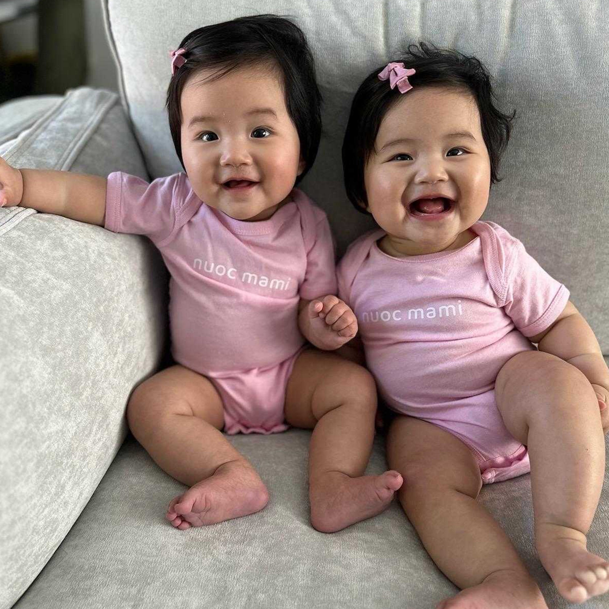 Two baby girls wearing matching pink Nuoc Mami onesies – Vietnamese-American baby outfit for sisters or friends